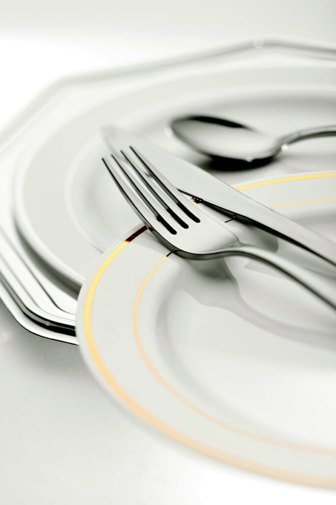 Close-up of elegant plates and silver cutlery, ideal for dining settings.