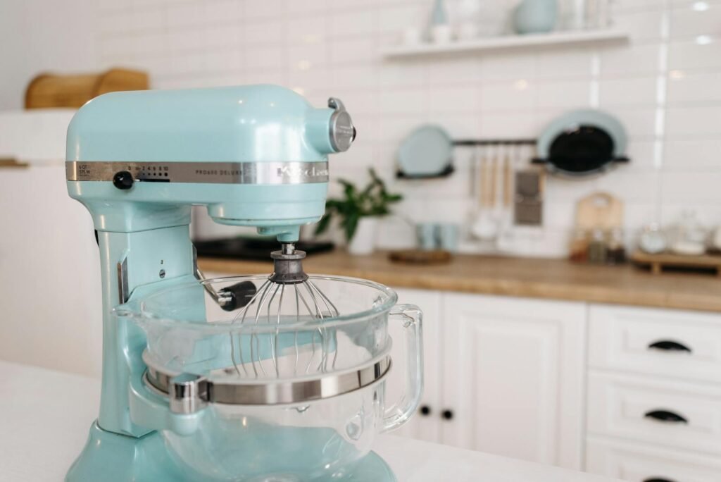A close-up of a blue stand mixer in a sleek, modern kitchen setting.